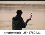 Man catching a small bass of the dock.