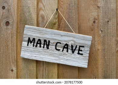 Man Cave Written On A Wooden Sign Hanging On A Wood Panel Shed Door.