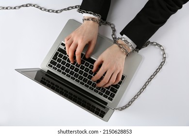 Man with chained hands typing on laptop against white background, top view. Internet addiction