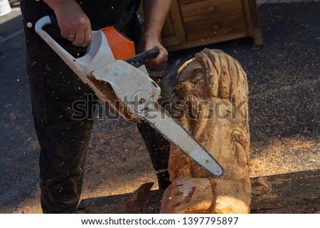 Man with a chainsaw creates a sculpture made of wood. Woodcarving