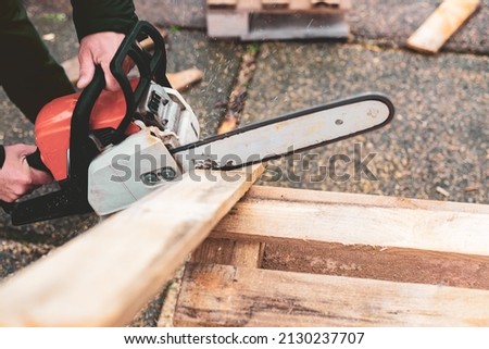 Man with chainsaw working with pallets