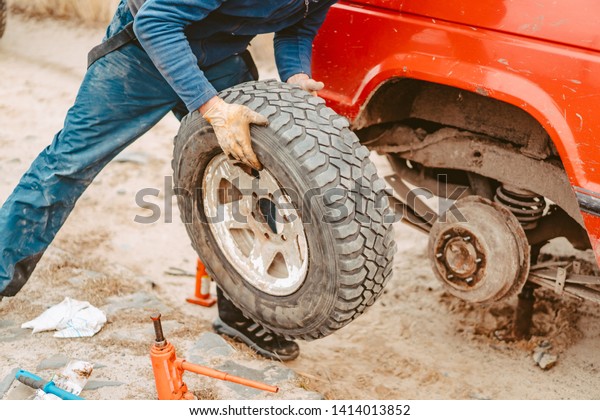 Man\
change the wheel manually on a 4x4 off road\
truck