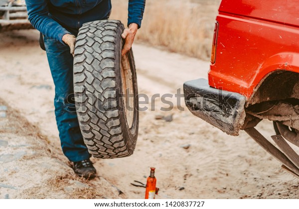 Man\
change the wheel manually on a 4x4 off road\
truck