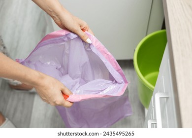 a man changes a garbage bag in a bucket. woman changing trash bag. empty trash bag. empty trash can. High quality photo