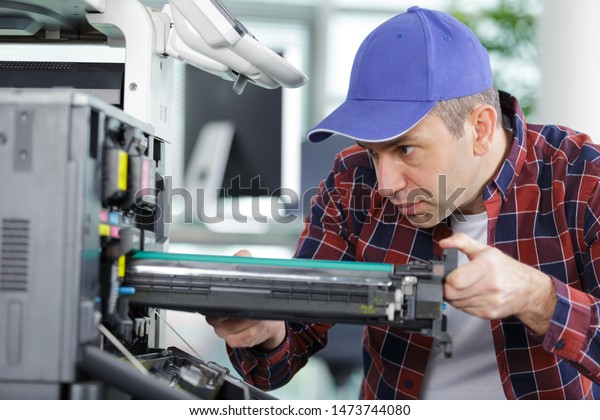 man changes\
the printer cartridge in the\
office