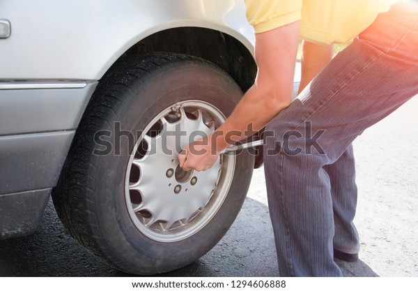 a man changes a\
wheel on a car outdoors