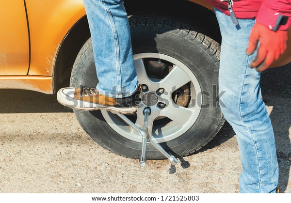 a man
changes wheels on a car. tire fitting. car service. tightens tight
wheel nuts with arms and legs. pulls a
key