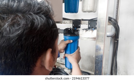 A Man Is Changing The Clean Water Filter, The Process Of Changing The Water Treatment Machine Filter With Shiny Light.