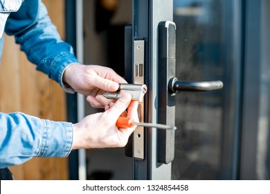 Man changing core of a door lock of the entrance glass door, close-up view with no face - Shutterstock ID 1324854458