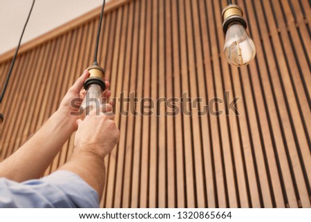 Man changing lamp light bulb indoors, closeup. Space for text