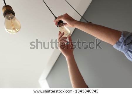Man changing lamp light bulb indoors. Space for text