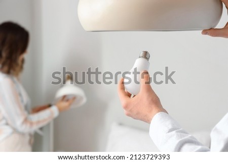 Man changing light bulb in hanging lamp at home, closeup