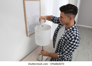 Man Changing Light Bulb In Lamp At Home