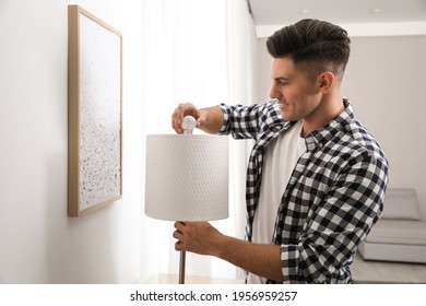 Man Changing Light Bulb In Lamp At Home