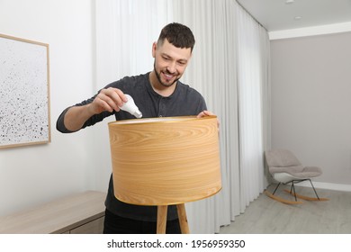 Man Changing Light Bulb In Lamp At Home