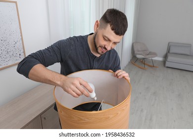 Man Changing Light Bulb In Lamp At Home