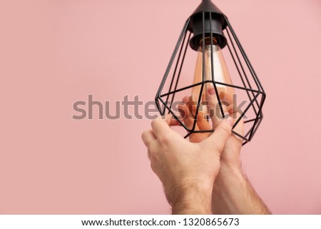 Man changing light bulb in lamp on color background. Space for text