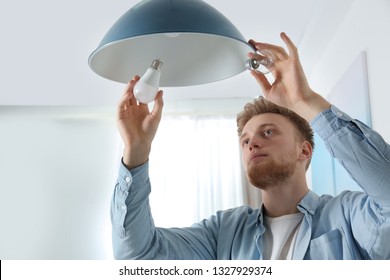 Man changing light bulb in pendant lamp indoors