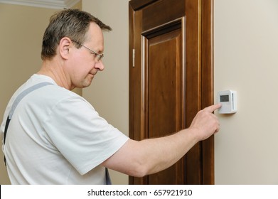 Man Is Changing  Settings Of A Thermostat. His Finger Is Pressing A Button.
