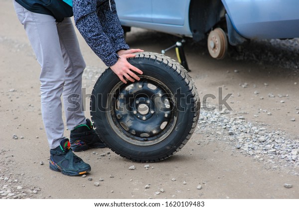 Man is changing\
tire with wheel on the car