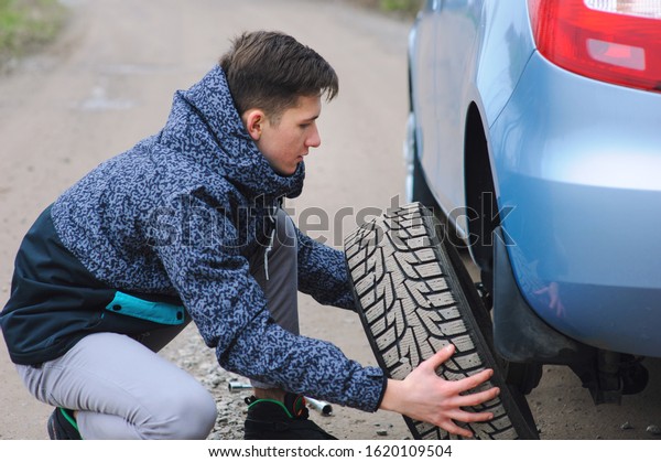 Man is changing\
tire with wheel on the car