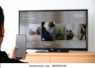 Man changing TV channel by his smartphone