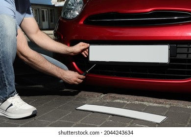 Man changing vehicle registration plate on car outdoors, closeup