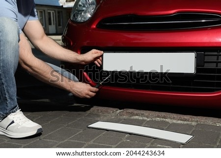Man changing vehicle registration plate on car outdoors, closeup