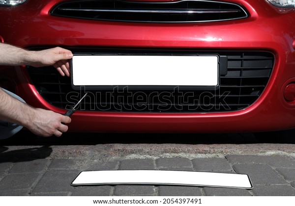 Man changing vehicle registration plate on car\
outdoors, closeup