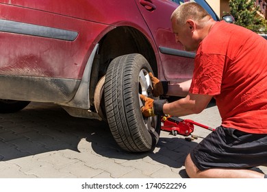 Man changing a wheel in his car. Damaged tire. Car repair on the road. - Shutterstock ID 1740522296