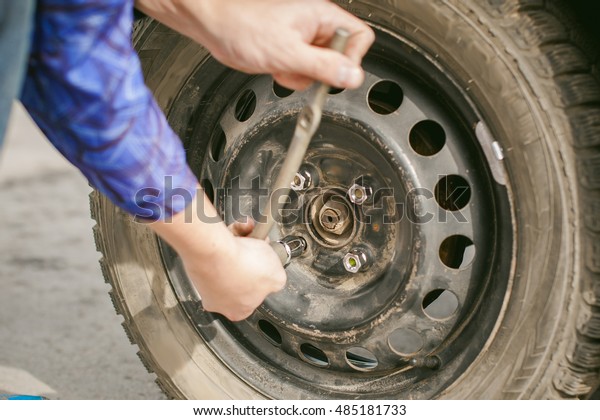 man changing a wheel on the road. on way there\
was breakage of wheel, puncture, necessary to lift the car jack and\
remove the wheel by loosening the nuts. road problems travelers. do\
it yourself