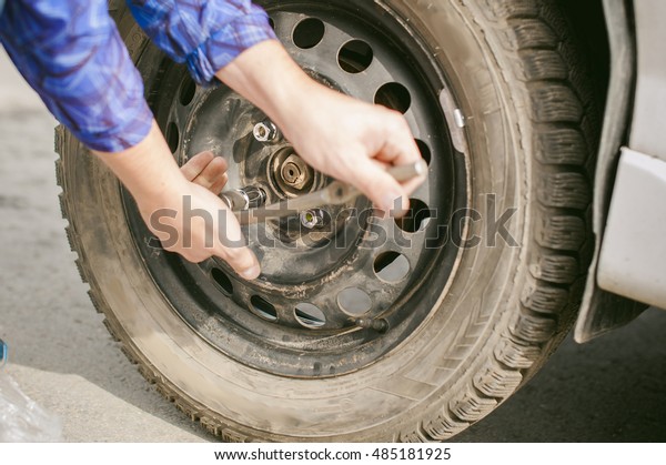 man changing a wheel on the road. on way there\
was breakage of wheel, puncture, necessary to lift the car jack and\
remove the wheel by loosening the nuts. road problems travelers. do\
it yourself