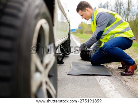 Man changing wheel on a roadside 