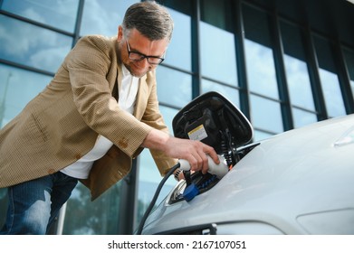 Man charges an electric car at the charging station.
