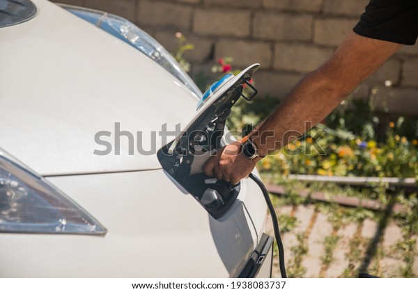 Man\
charges an electric car at the charging\
station\
