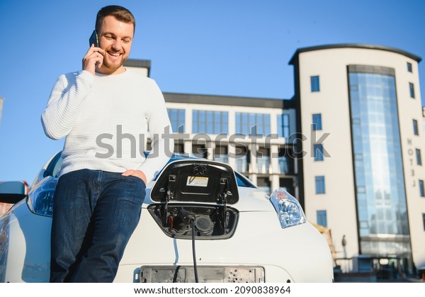 Man\
charges an electric car at the charging\
station