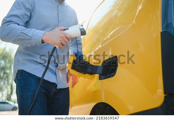 Man\
charges an electric car at the charging\
station