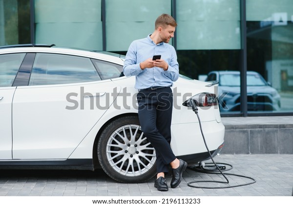 Man\
charges an electric car at the charging\
station.