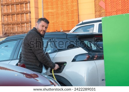 A man charges his electric car in a shopping mall
