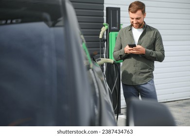 A man charges his modern electric car. The concept of green energy. - Powered by Shutterstock