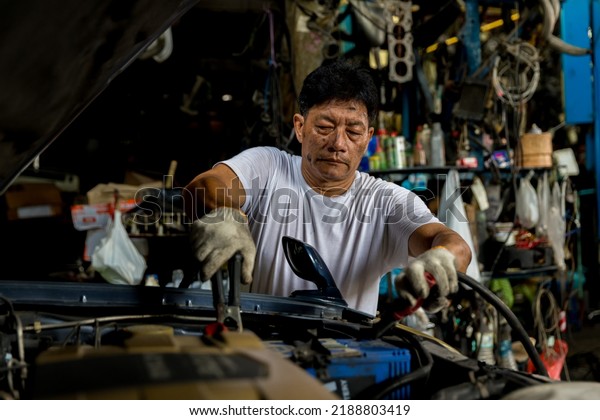 Man charging battery car with electricity\
cables. Engine engineer is charging car battery because car battery\
is depleted. concept car maintenance\
