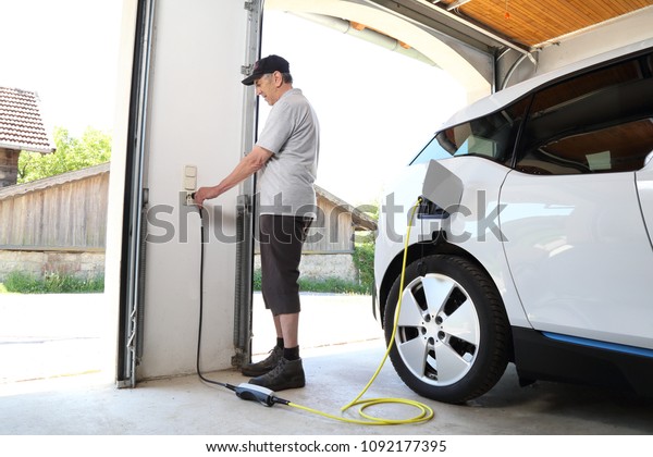 A Man\
Charging Electric car  at outlet at\
home