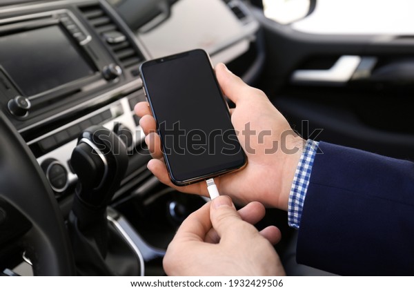 Man charging phone\
with USB cable in car