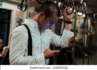 A Man Checing His Phone While He Took A Skytrain To Get Back Home Once Finish His Work.