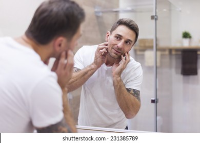 Man check condition of his skin in mirror reflection 