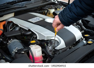 A man check the oil in modern car motor safety routine before drive.