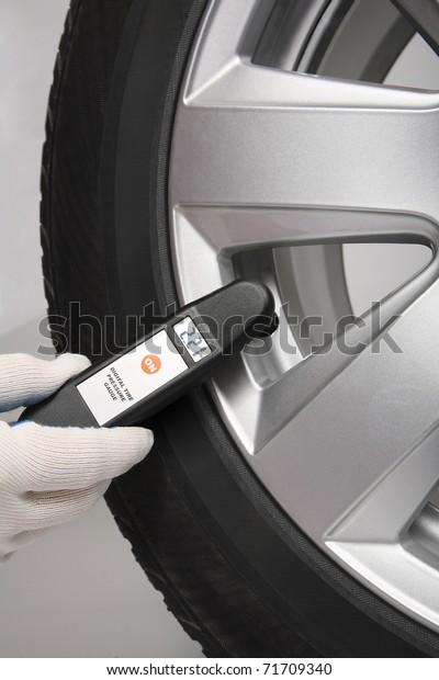 Man\
check the pressure in a car tire with digital\
meter