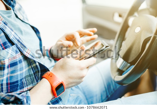 A man in a checked shirt and red\
watch is holding a tablet in his hands in search of a route before\
traveling by car. The concept of tourism and\
travel.