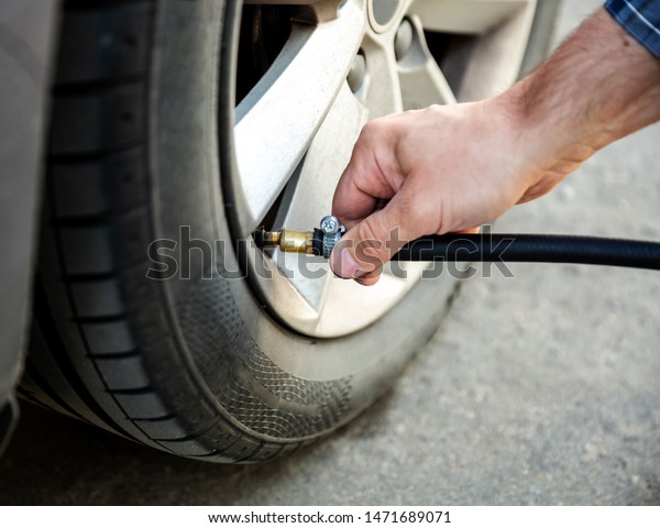 Man checking air pressure and filling air in the\
tires of his car closeup