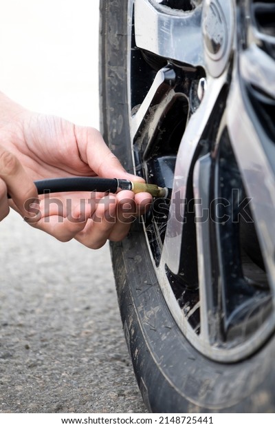 Man checking air pressure and filling air in the\
tires of car. Concept\
picture